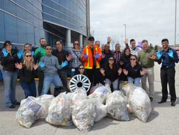 A group of employees pose behind bags of garbage.