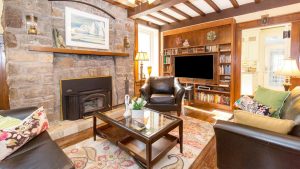 Features of the family room include a French door entrance, an exposed beamed ceiling, a built-in floor-to-ceiling entertainment unit and shelves and wood-burning fireplace with a stone surround.