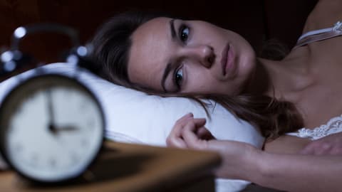 Une femme couchée qui fait de l'insomnie et qui regarde son cadran