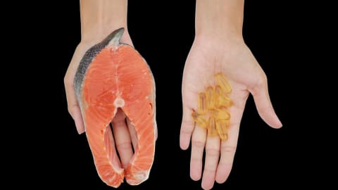 Deux mains, l'une contenant des suppléments d'oméga-3, l'autre un morceau de saumon.