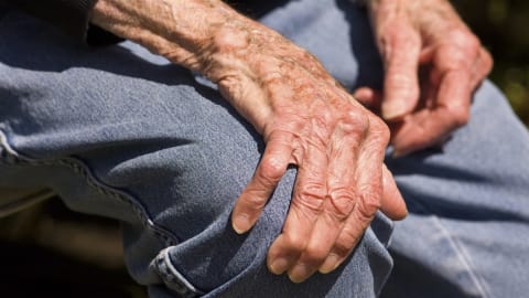 La main d'un vieil homme déposée sur son genou