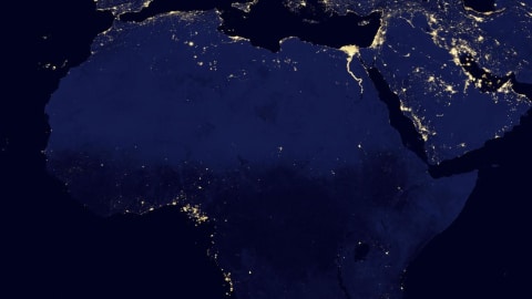 Le Nord du  continent africain vu de l'espace, la nuit, alors que peu de points lumineux indiquent la présence d'éclairage électrique.