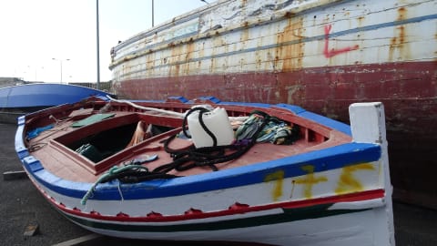 Une barque abîmée gît dans un port.
