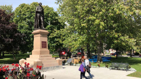 Deux piétons passent devant l'immense statue de Sir John A. Macdonald.