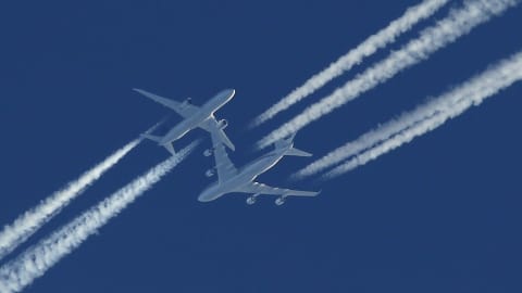 Deux avions commerciaux se croisent dans un ciel bleu. 