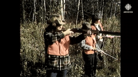 Trois femmes avec des dossards oranges tirent au long fusil dans un forêt.