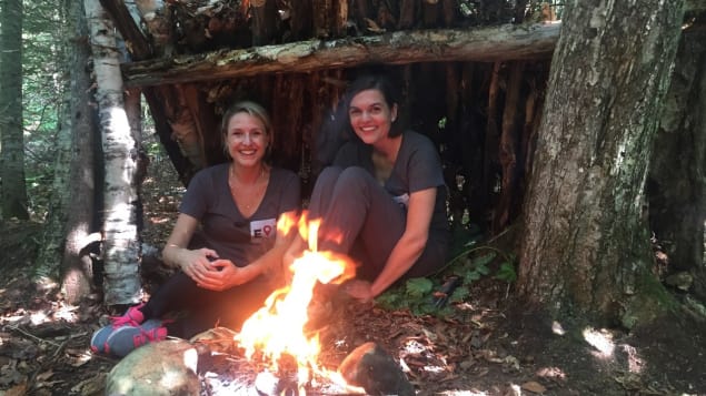 Deux femmes sous un abri en bois avec un feu de camp devant elle. 