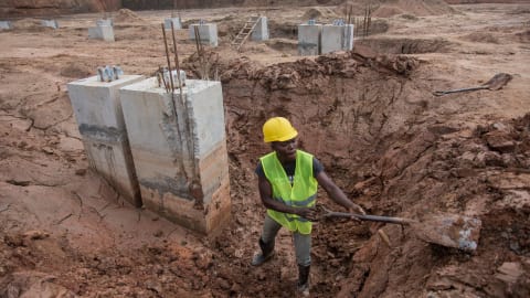 Un travailleur creuse avec une pelle dans un chantier de construction.