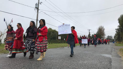 Des femmes et des hommes vêtus de rouge marchent en mémoire des femmes autochtones disparues ou assassinées.