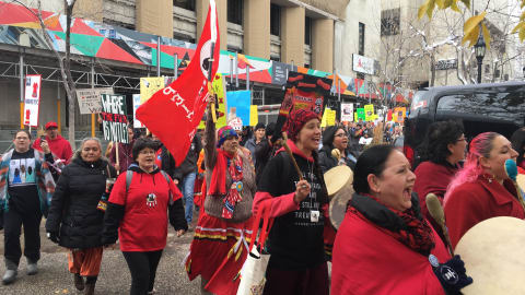 Des femmes, tambours et affiches à la main, marchent dans une rue de Calgary.