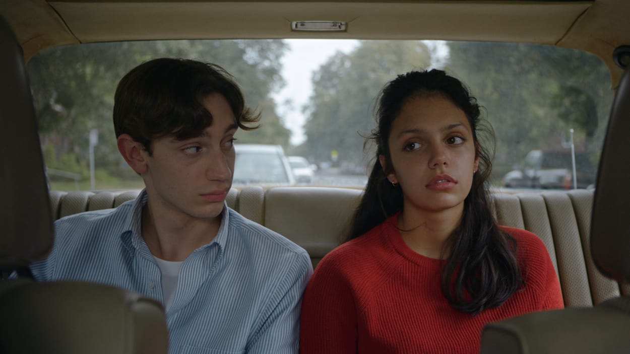 Un jeune homme et une jeune femme sont assis sur le siège arrière d'une voiture.