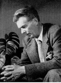 Monochrome portrait of Aldous Huxley sitting on a table, facing slightly downwards.