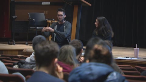 Deux personnes s'adressent à un groupe d'étudiants dans un auditorium. 