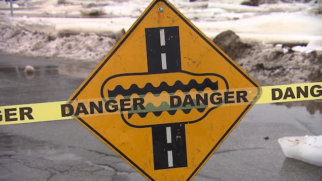 Un panneau de signalisation indique que des inondations peuvent se produire sur la chaussée.