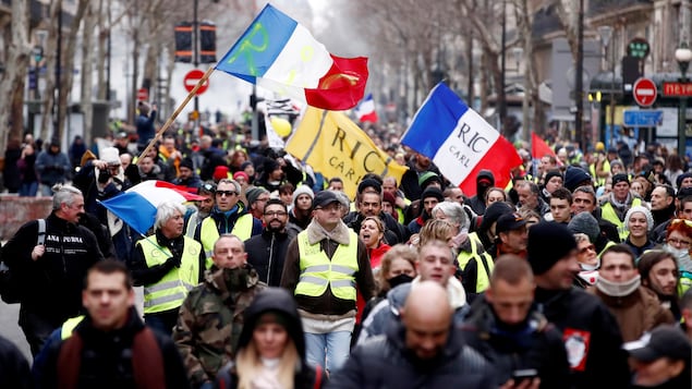 Une foule marche avec des drapeaux français.