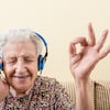 Une dame agée qui écoute de la musique avec un sourire au visage. 