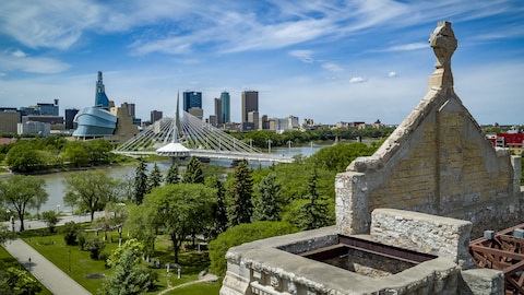 Une vue aérienne depuis les murs de pierre de l'ancienne cathédrale de Saint-Boniface, où l'on voit l'esplanade Louis-Riel, le pont Provencher, le Musée canadien pour les Droits de la personne et les immeubles de Winnipeg.