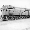 Photo en noir et blanc d'une locomotive de train du Canadian National avec un homme dans la cabine avant.