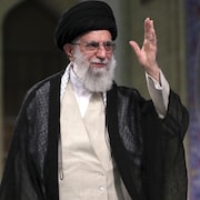 Gros plan de l'ayatollah Ali Khamenei, qui a une main en l'air.