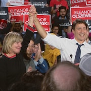Justin Trudeau soulève la main d'Eleanor Olszewski vers le ciel en signe de victoire.