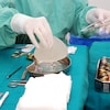 Une infirmière tient dans sa main un implant mammaire.