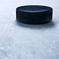 Une rondelle de hockey en gros-plan sur la glace d'un patinoire.