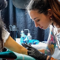 Une femme en train de tatouer une femme.