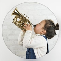 Une jeune fillette asiatique souffle dans un cornet (instrument de musique ressemblant à une trompette plus courte et plus grosse)