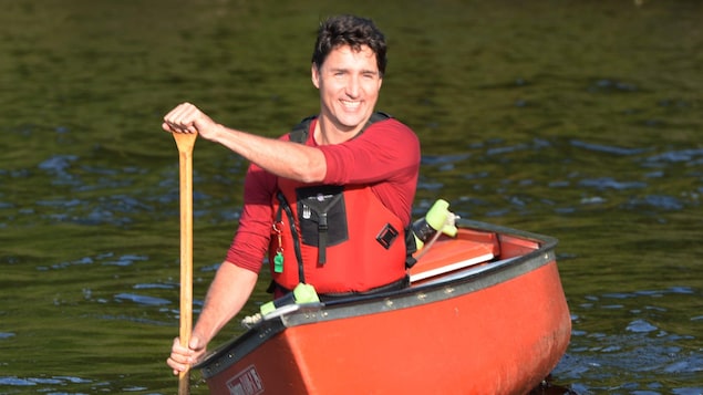 Justin Trudeau sourit, seul dans un canot sur un lac.