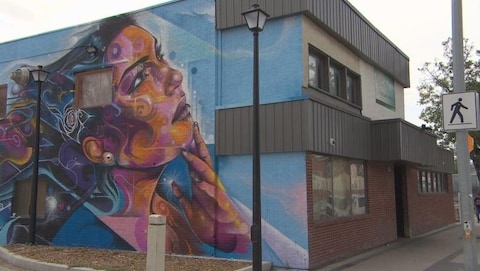 Un édifice avec une peinture murale d'une femme qui regarde vers le ciel.