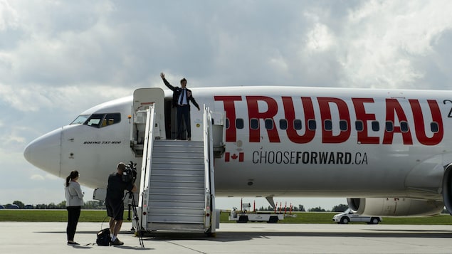 Justin Trudeau envoie la main du haut de la rampe d'accès menant à l'avion du Parti libéral du Canada.