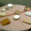 Des morceaux de fromage sont présentés sur une table ronde décorée d'une nappe Vichy.