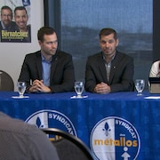Les trois candidats bloquistes, ensemble, face à des personnes dans une salle, lors d'une conférence de presse.