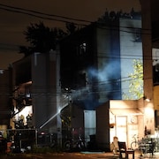 Des pompiers éteignent le feu d'un immeuble.