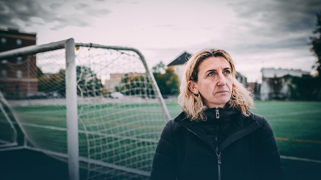 Marinette Pichon regarde au loin en se tenant devant un but de soccer.
