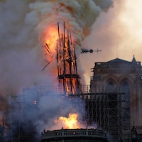 La flèche de la cathédrale, en feu, commence à s'écrouler. 