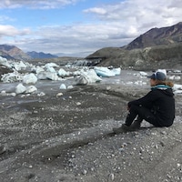 Une habitante de Whitehorse, Haley Digel, assise par terre observe le 15 juillet un grand espace se trouvait un lac du glacier Donjek.
