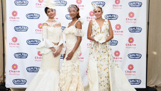 Trois femmes posent dans des robes de mariage faites de papier hygiénique.