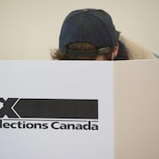 Un jeune homme passe au vote dans une urne d'Élections Canada.