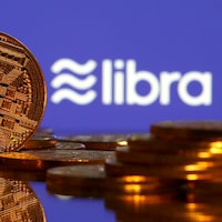 Pièces de monnaie placées devant un écran où il est écrit « libra ».