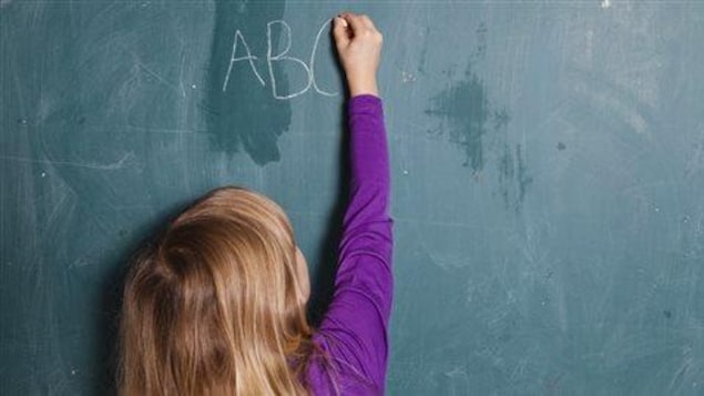 Enfant écrivant les lettres ABC à la craie sur un tableau noir