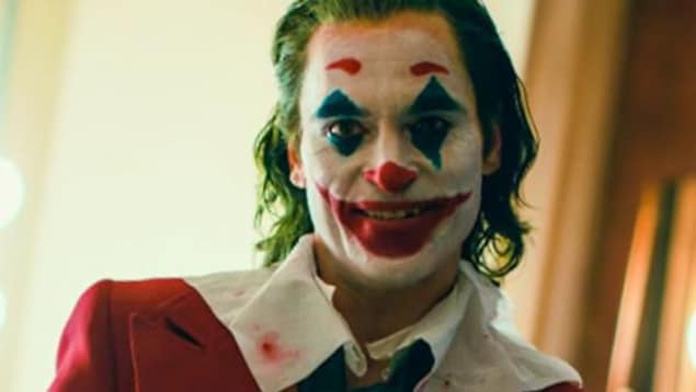 Un homme souriant (Joaquin Phoenix) portant un maquillage de clown.