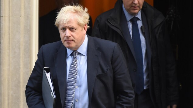 Boris Johnson marche, un cartable sous le bras.