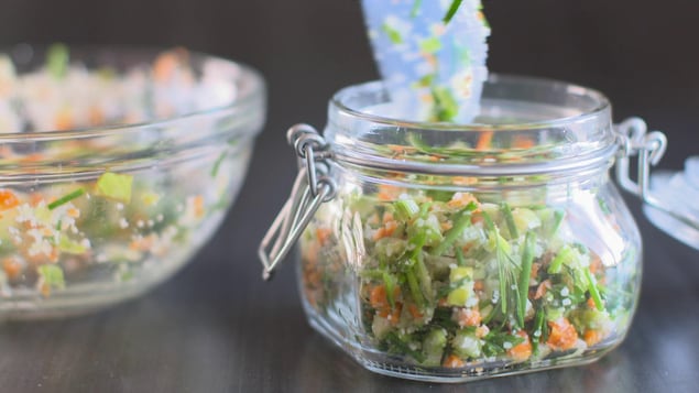 Les herbes, le sel et les petits morceaux de carottes et de céleri sont dans un pot en verre transparent.