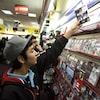 Un jeune prend un jeu sur une tablette d'un magasin de jeux vidéo. 