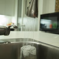 De l'eau coule d'un robinet d'un évier de cuisine dans un verre.