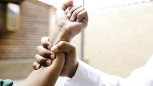 La main d'un élève qui empoigne l'avant-bras d'une élève, en gros plan