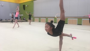 Lori Li Blanchard, une jambe haut dans les airs fait une pose de gymnastique rythmique. 