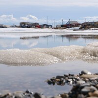 Un village sur la côte derrière une étendue d’eau à moitié gelée. 