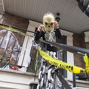 Préparations de l’Halloween sur le Plateau-Mont-Royal, à Montréal, Québec. 
Un jeune garçon revêtu d'un costume de squelette et arborant un masque sur un balcon décoré de Montréal.